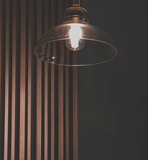 Contemporary pendant light illuminating a wooden panel wall creates a warm, inviting interior atmosphere.