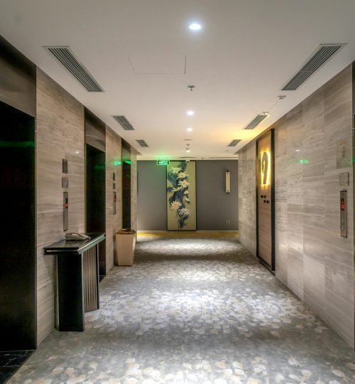 Spacious hotel hallway with elevators and contemporary decor.